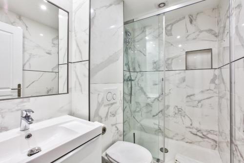a white bathroom with a shower and a sink at 65-FRENCH CANCAN ST DENIS in Paris