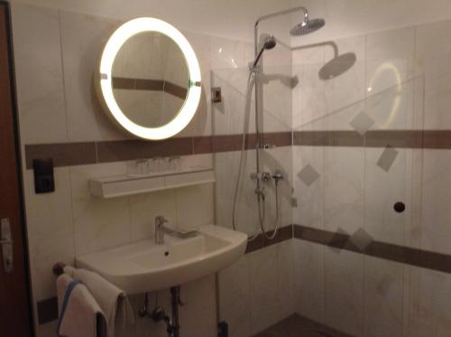 een badkamer met wastafel en douche met spiegel bij Ferienwohnungen Salmen in Pörtschach am Wörthersee