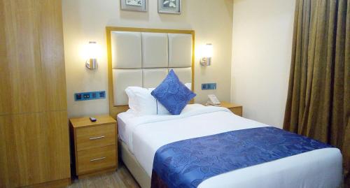 a hotel room with a bed with a blue pillow on it at Days Hotel Dhaka in Dhaka