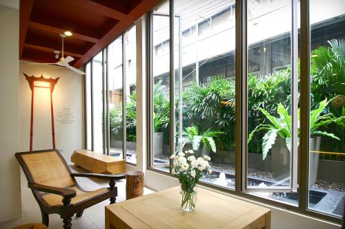 a room with a table with a vase of flowers on it at CHERN Bangkok in Bangkok