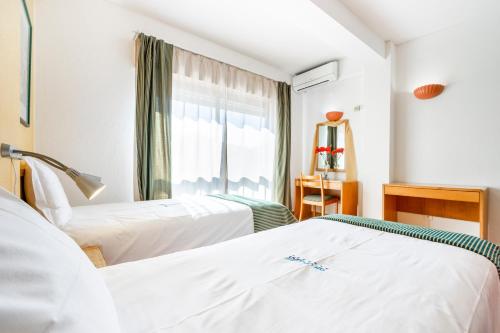 dwa łóżka w pokoju z oknem w obiekcie Altura Inn Beach w mieście Altura