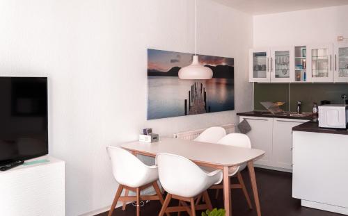 a dining room with a table and white chairs at Tarata Wohnung in Halle an der Saale