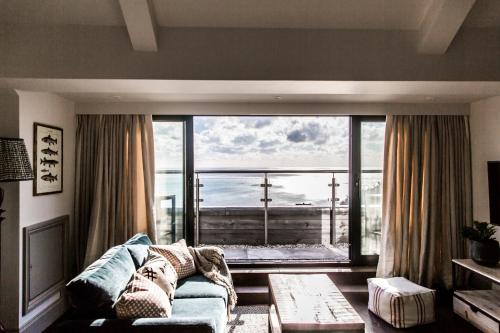 a living room with a couch and a large window at Gara Rock in Salcombe