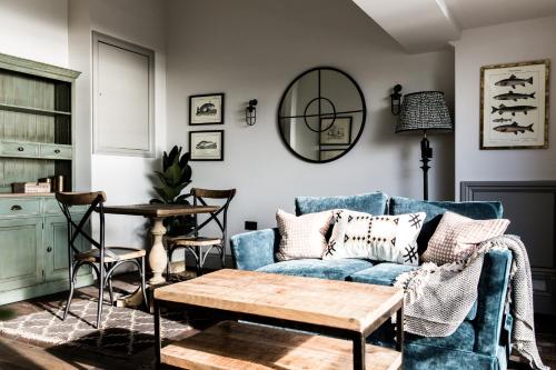 a living room with a blue couch and a table at Gara Rock in Salcombe