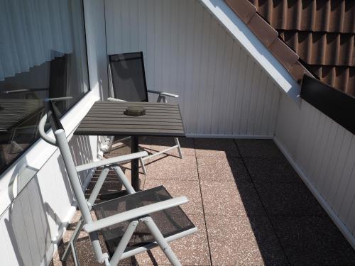 a porch with a wooden table and a chair at Hotel Meeresruh Garni in Cuxhaven