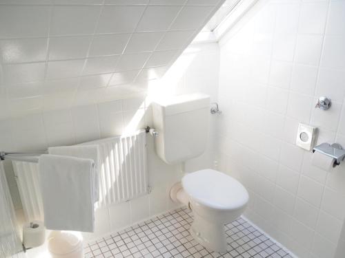 a white bathroom with a toilet and a staircase at Hotel Meeresruh Garni in Cuxhaven