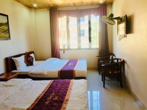 a bedroom with two beds and a desk and a window at May Hong Hotel in Sapa