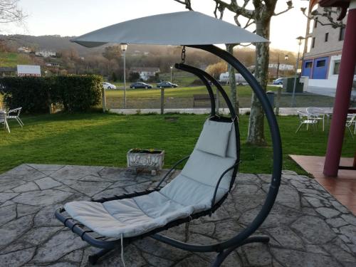 a swinging chair with an umbrella on a patio at Atxispe Etxea Casa Rural in Laukiz