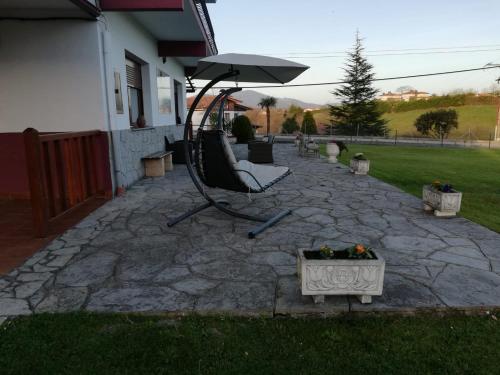 a patio with a bench and an umbrella at Atxispe Etxea Casa Rural in Laukiz