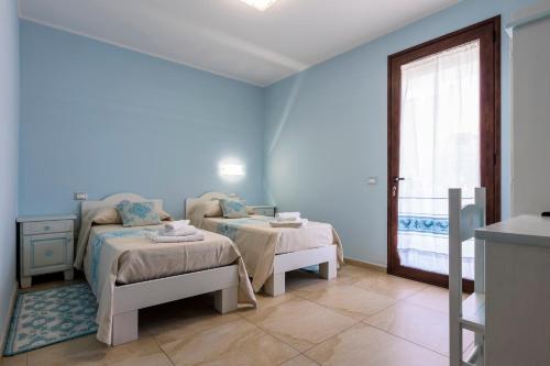 a blue room with two beds and a window at Sardinia for you in Oristano