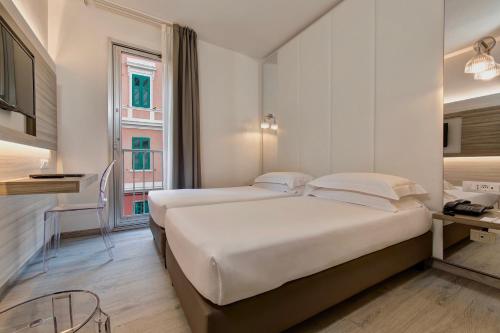 a white bedroom with two beds and a desk at Hotel San Giusto in Trieste