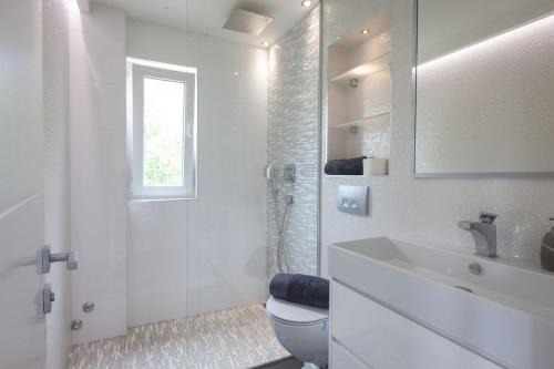a white bathroom with a toilet and a sink at Villa Retro fusion a luxury villa in Tucepi in Tučepi