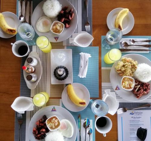 a table with plates of breakfast food on it at Wuthering Heights Bed & Breakfast by the Sea in Dumaguete