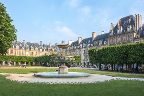 a fountain in a park in front of a large building at Les Tournelles in Paris
