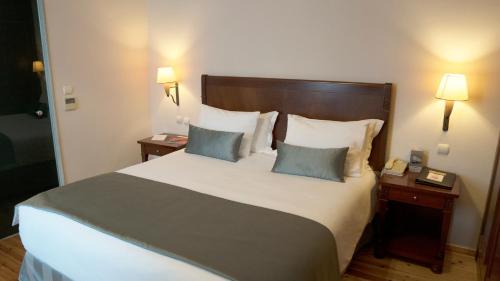 Capsis Bristol Boutique Hotel في سلانيك: غرفة نوم بسرير كبير مع مواقف ليلتين ومصباحين