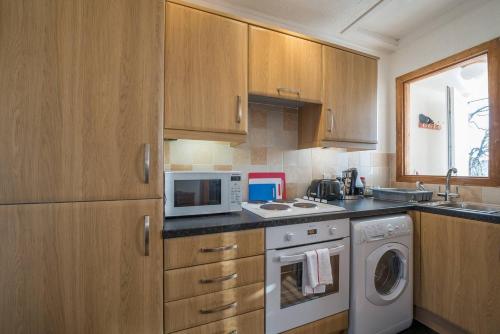 cocina con armarios de madera, lavadora y secadora en Brucefield Avenue en Dunfermline