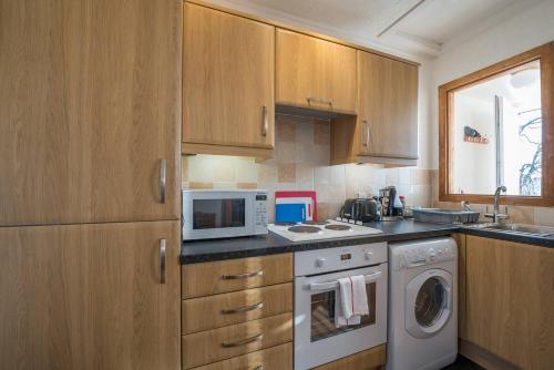 cocina con armarios de madera, lavadora y secadora en Brucefield Avenue, en Dunfermline