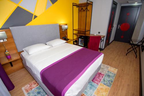 1 dormitorio con 1 cama grande y pared colorida en Hotel Adora, en Tiflis