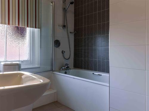 un bagno bianco con vasca e lavandino di The White Lion Hotel ad Aldeburgh