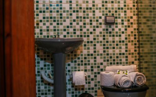 a bathroom with a sink and a toilet with towels at Pousada e Chalés Itamoara in São Thomé das Letras