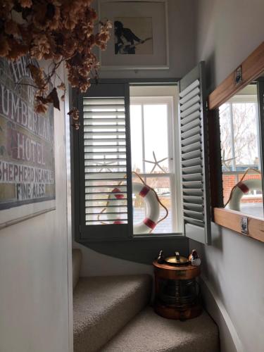 a room with a staircase with two windows and a table at waves whitstable in Whitstable