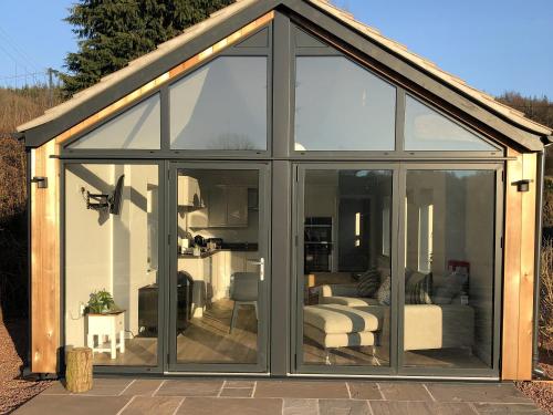 a conservatory with glass doors on a patio at Welsh Marches at Upper Glyn Farm in Chepstow