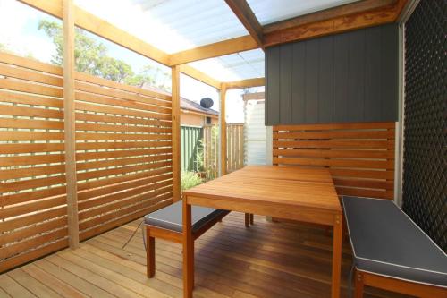 a wooden deck with a wooden table and a bench at Pacific Terraces 16, 38 Pacific Street in Crescent Head