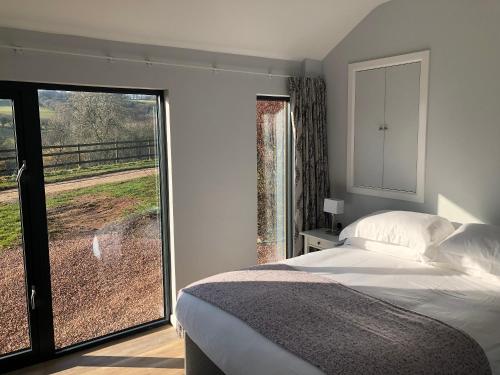 - une chambre avec un lit et une porte coulissante en verre dans l'établissement Welsh Marches at Upper Glyn Farm, à Chepstow