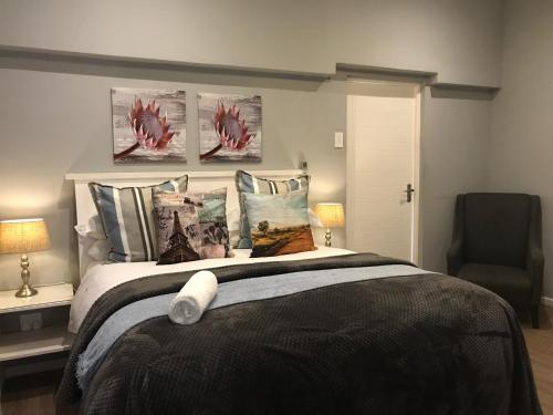 a bedroom with a bed with pillows and a chair at Anathi Hotel in Kokstad