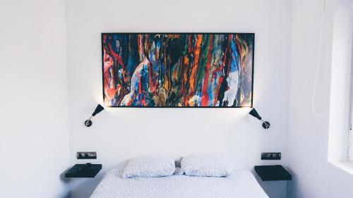 a painting hangs above a bed in a room at APARTAMENTO ROMANTICO WiFi FREE PARKING AREA in Donostia-San Sebastián