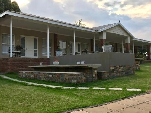 a house with a porch and a lawn at Anathi Hotel in Kokstad