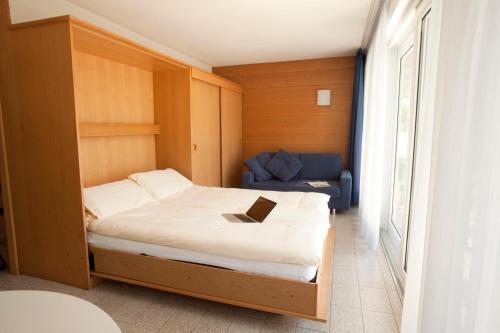 1 dormitorio con 1 cama con ordenador portátil en Casa Toblini al Lago on the beach, en Nago-Torbole