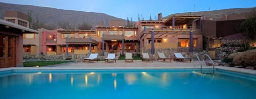 a swimming pool with chairs and a house in the background at Las Marías Hotel Boutique in Tilcara