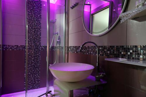 a purple bathroom with a sink and a shower at Hotel Al Castello in Pomezia