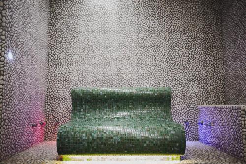 a green chair in a room with a wall at Hotel Fiera Wellness & Spa in Bologna