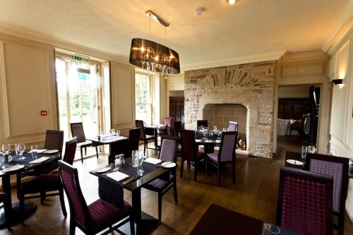 a dining room with tables and chairs and a fireplace at Best Western Plus Sheffield Mosborough Hall Hotel in Sheffield
