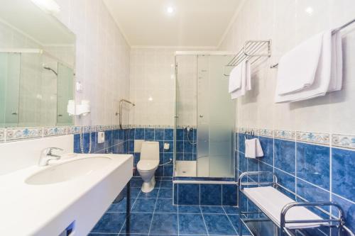 a blue tiled bathroom with a sink and a toilet at Ukraina Hotel in Simferopol