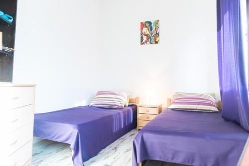 two beds in a room with purple sheets at French Balkony Apartment in Belgrade