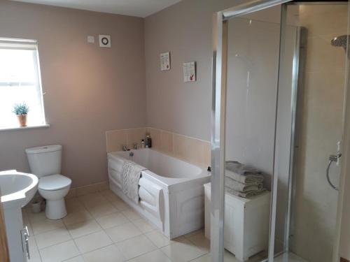 a bathroom with a tub and a toilet and a sink at Ballymultimber Cottages in Limavady