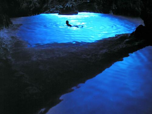 a person swimming in a pool of water at night at apartmani vraničić in Vis