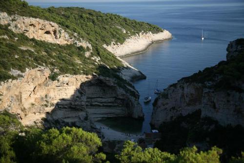 a view of a cliff with boats in the water at apartmani vraničić in Vis