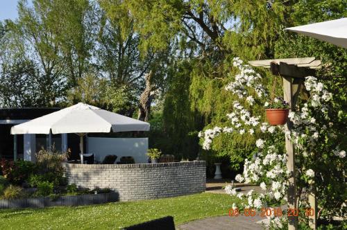 a garden with white flowers and an umbrella at Resort De Vlasschure in Wissenkerke