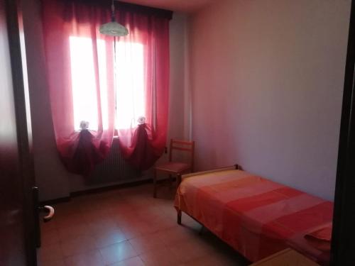 a bedroom with red curtains and a bed and a window at La Casa dei Gelsomini in Arsiero