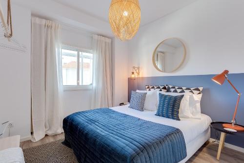 een slaapkamer met een bed met een blauwe deken en een spiegel bij DA'HOME - Boavista Brightful Apartment in Porto