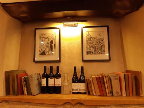 a shelf with bottles of wine and books at The Crown at Wells, Somerset in Wells