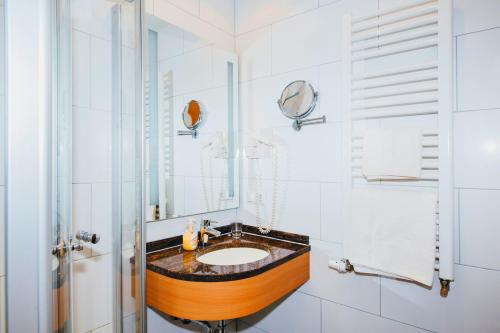 W łazience znajduje się umywalka i lustro. w obiekcie Hotel Central w mieście Weil am Rhein
