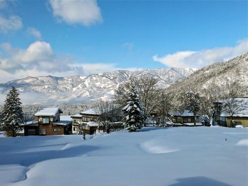 a snow covered village with mountains in the background at Schanze Nozawa in Nozawa Onsen