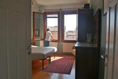 Eine Frau, die aus einem Fenster in einem Zimmer schaut. in der Unterkunft B&B S.Marco in Venedig