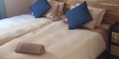 two beds with blue pillows and a towel on them at Lodge Strand (The) in Strand