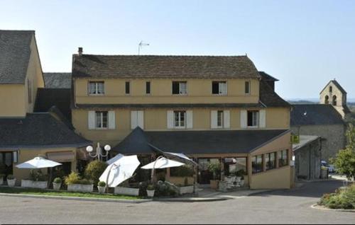 a large yellow building with umbrellas in front of it at Logis Hôtel de la Tour in Masseret